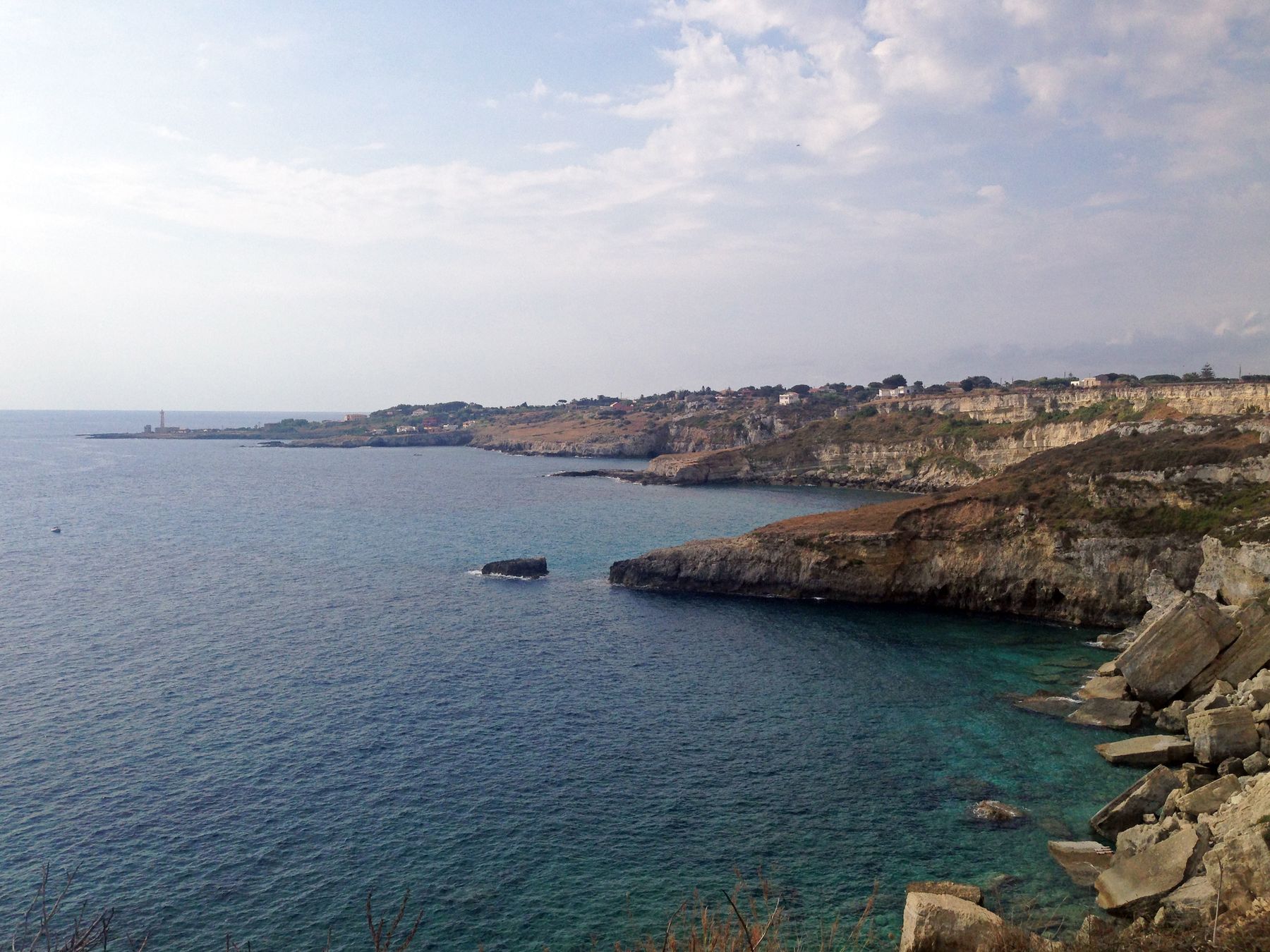 La costa alta a nord del faro, con il mare limpido sotto gli scogli